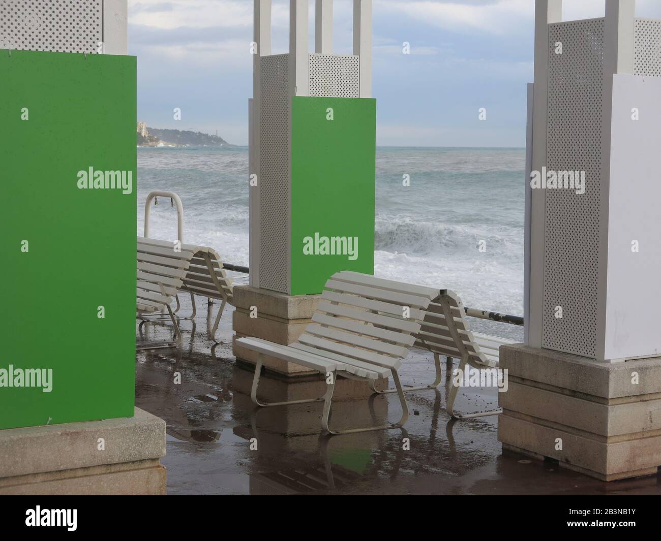 Grauer Himmel und stürmisches Meer Anfang März mit leeren Sitzplätzen an der Strandpromenade von Anglais in Nizza an der französischen Riviera. Stockfoto