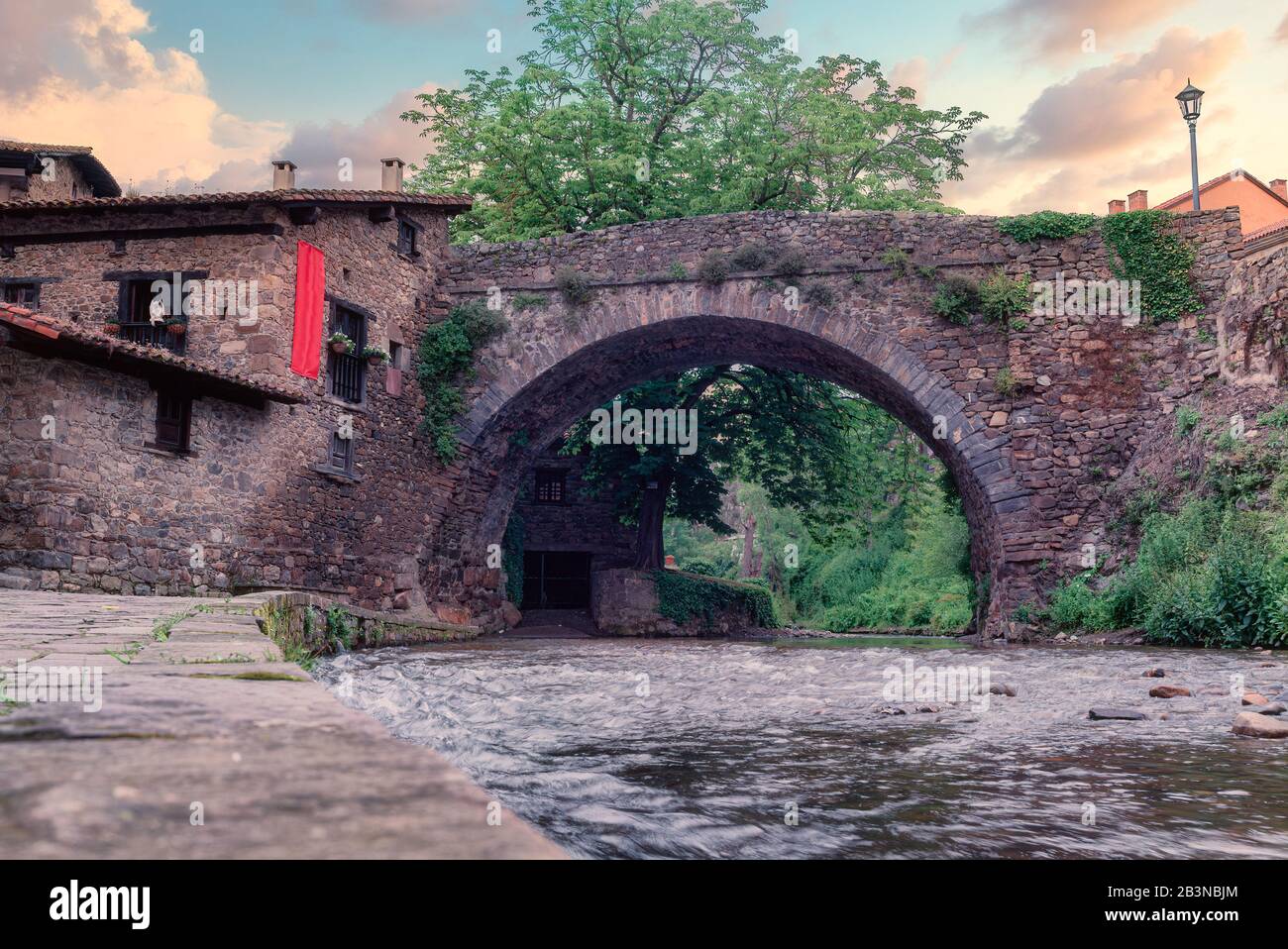 Die mittelalterliche Bogensteinbrücke von San Cayetano über den Fluss Quieviesa in Pobes, umgeben von mittelalterlichen Gebäuden, das Bild aus einem niedrigen Winkel Stockfoto