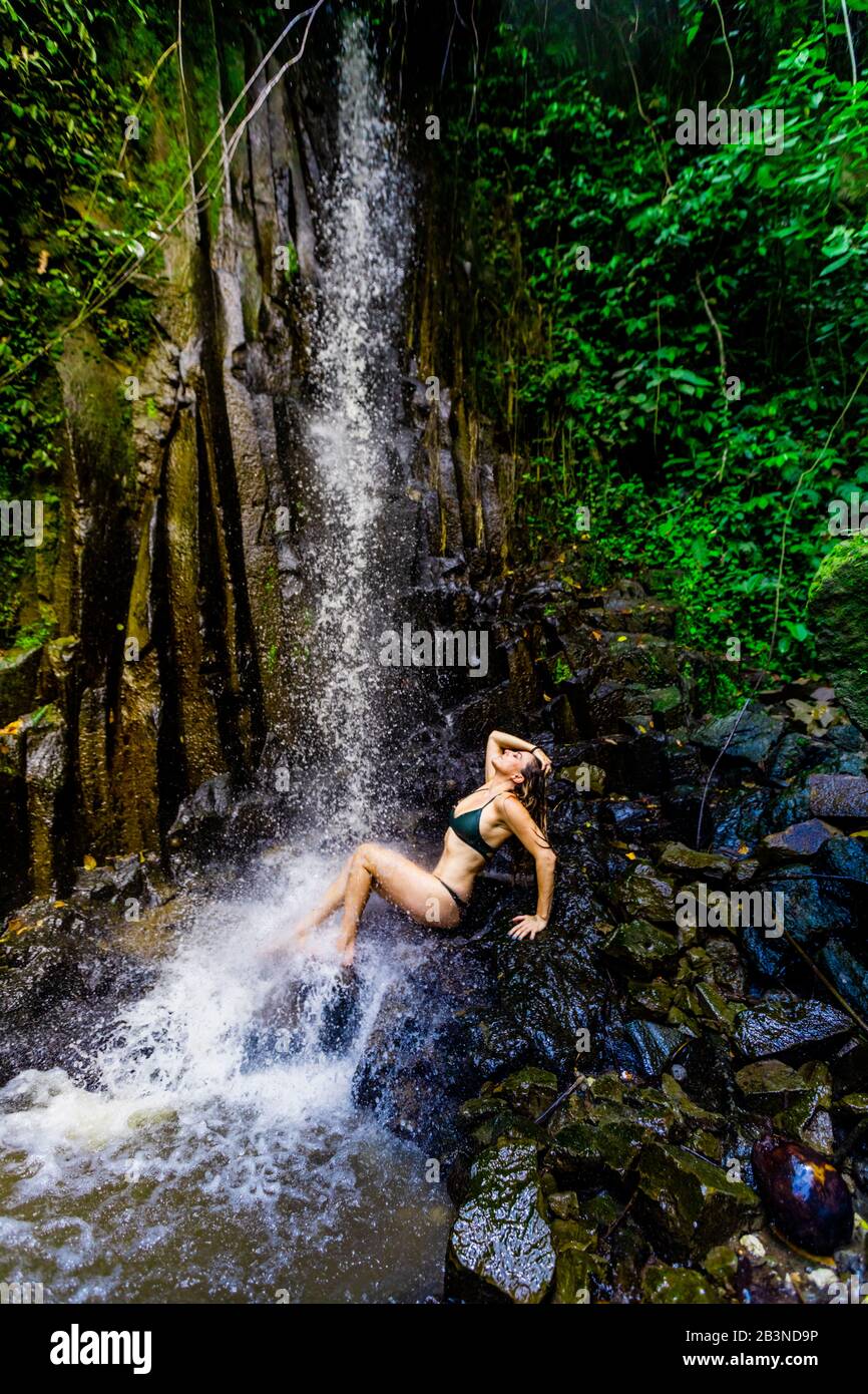 Frau posiert für ein Bild unter einem Wasserfall am Beji Guwang Hidden Canyon, Bali, Indonesien, Südostasien, Asien Stockfoto