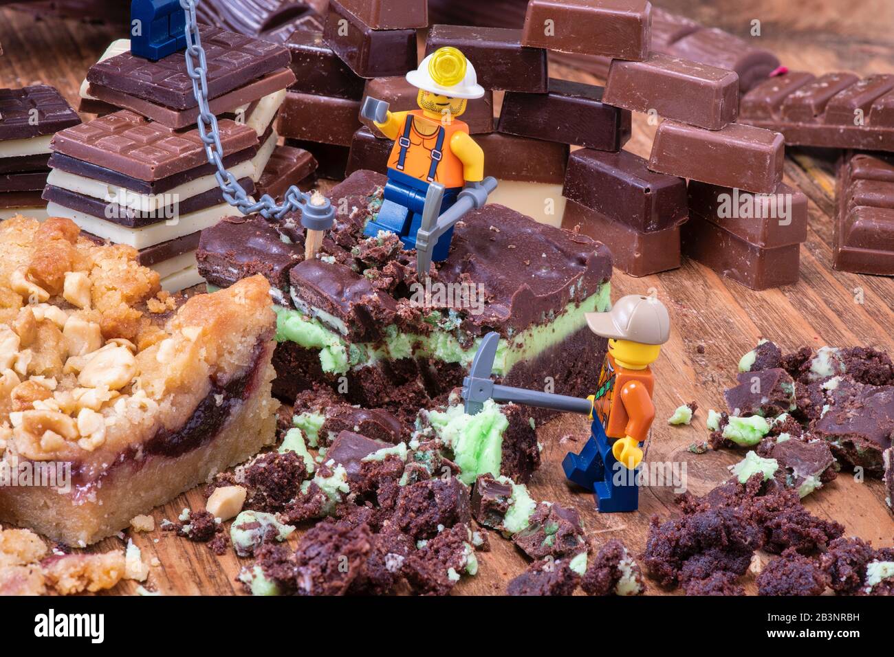 Schokolade- und Kuchenbergbau. Toy Lego Männer mit Kuchen und Schokolade Stockfoto