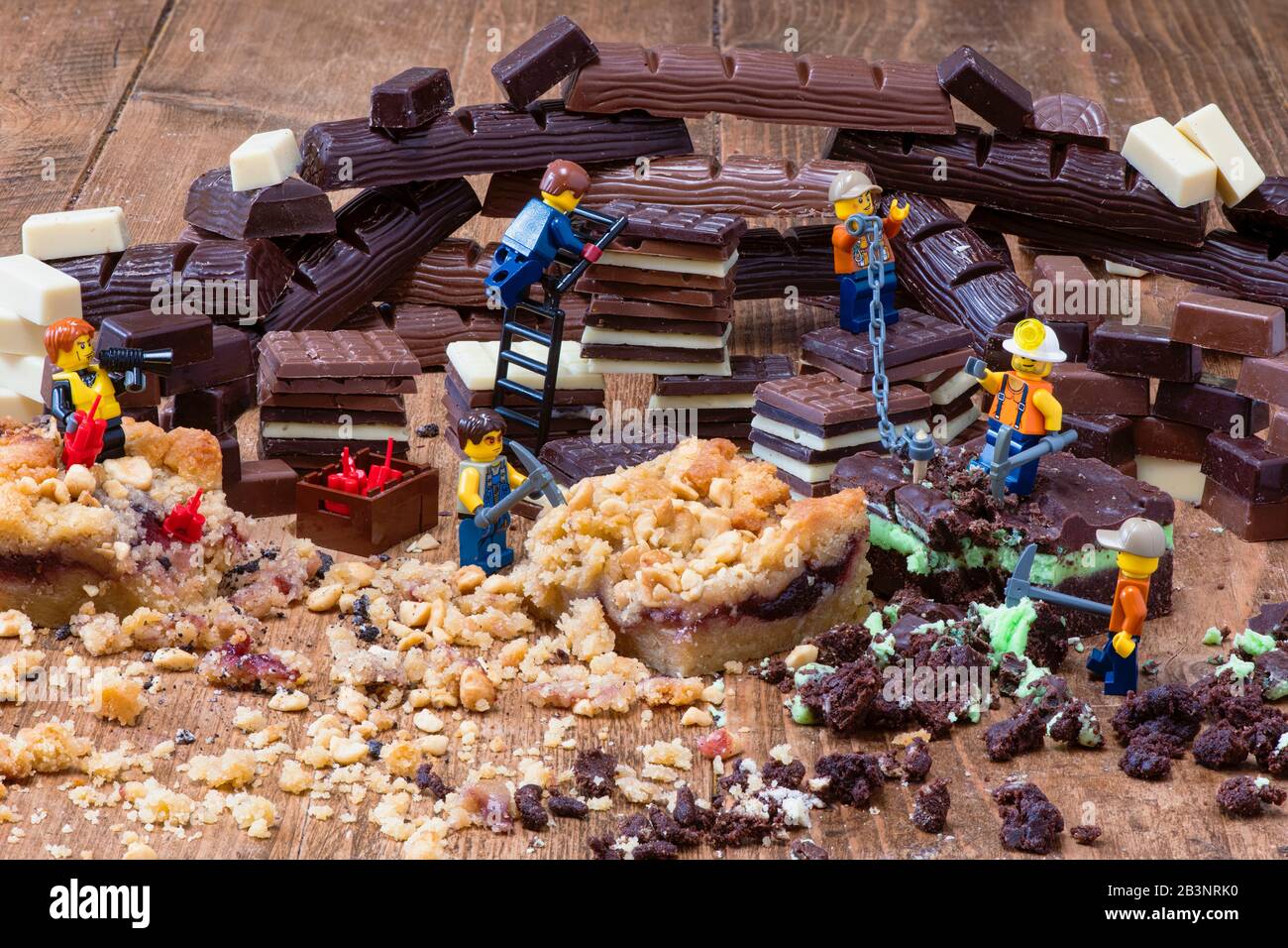 Schokolade- und Kuchenbergbau. Toy Lego Männer mit Kuchen und Schokolade Stockfoto