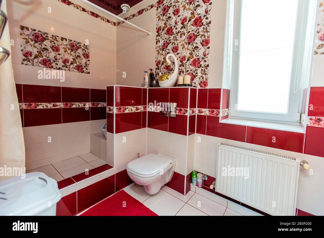 Großes Badezimmer im Cottage in rot-weißen Farben. Kastanienbraune und weiße Fliesen, Fliesen mit roten Farben. Toilette, Dusche. Weiße und kastanienbraune Fliesen auf dem fl Stockfoto