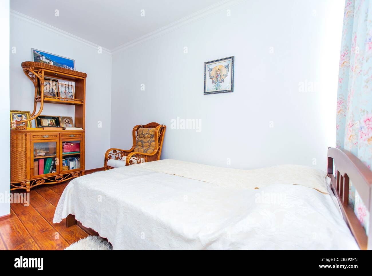 Schlafzimmer mit einem großen Doppelbett aus Holz, einem Schaukelstuhl und vielen christlichen Ikonen auf der Seitenwand gegenüber dem Bett. Stockfoto