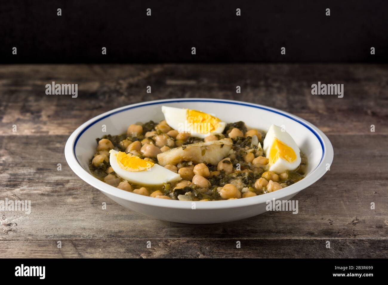 Kichererbseneintopf mit Spinat und Kabeljau oder Potaje de vigilia auf Holztisch Stockfoto