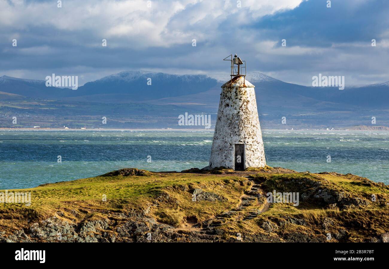 Der Leuchtturm Twr Bach auf der Insel Llanddwyn mit schneebedeckten Snowdonia Bergen im Hintergrund, Anglesey Stockfoto