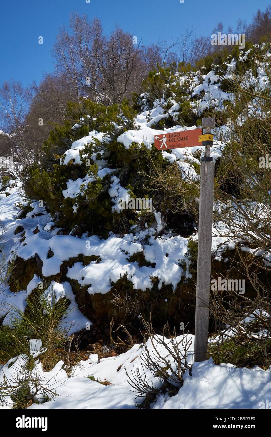 Wegweiser umgeben vom Schnee des Wanderweges PR.AS-15.1, der auf den See Lago del Valle zeigt (Valle del Lago, Naturpark Somiedo, Asturien, Spanien) Stockfoto