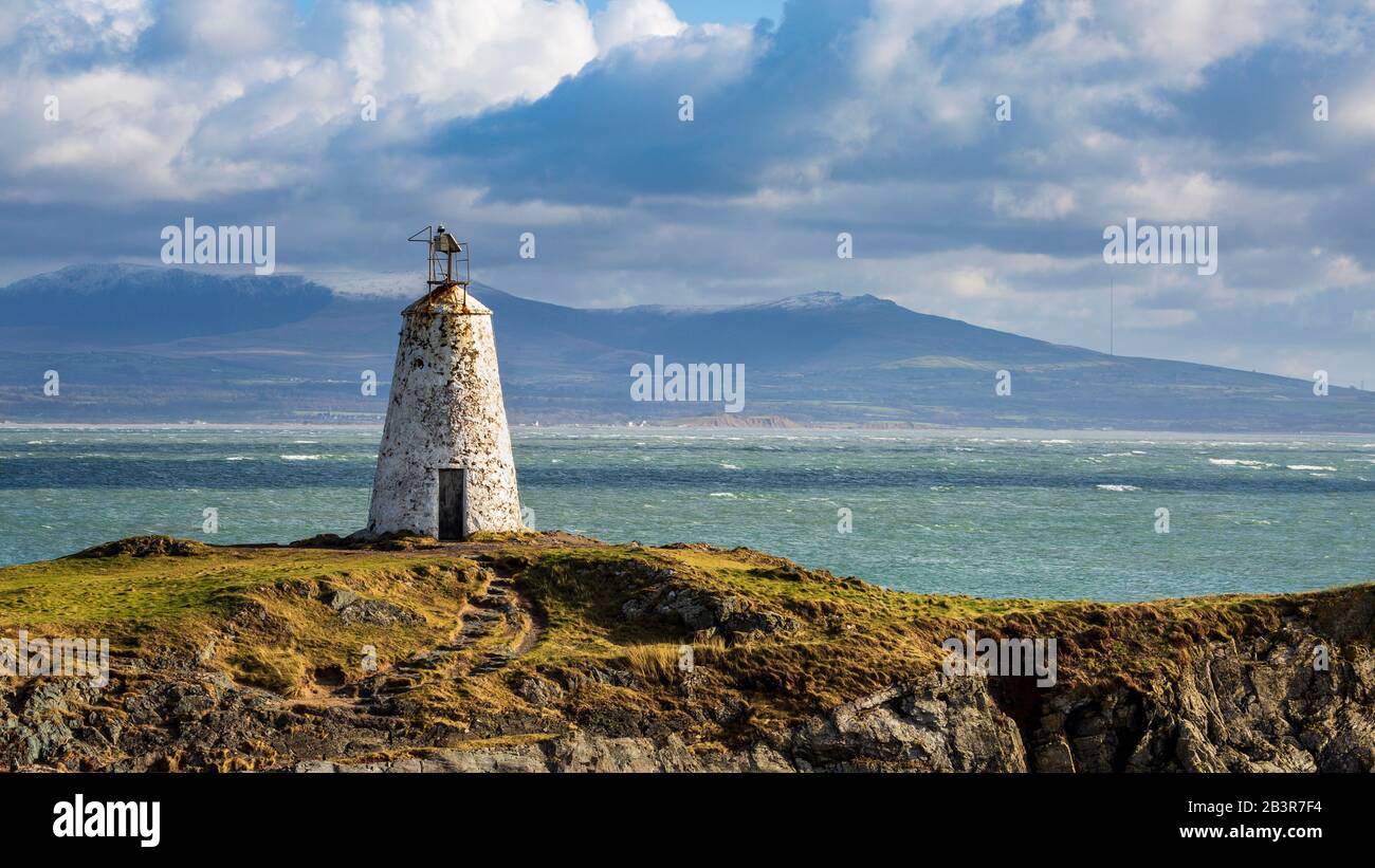 Der Leuchtturm Twr Bach auf der Insel Llanddwyn mit schneebedeckten Snowdonia Bergen im Hintergrund, Anglesey Stockfoto