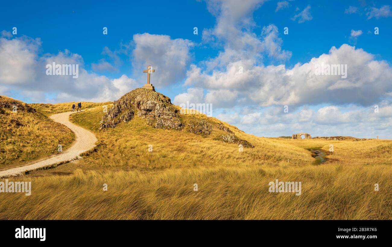 Ein Blick auf den Küstenweg und die Ruinen der St. Dwynwen Kirche und die modernen und keltischen Kreuze auf Llanddwyn Insel, Anglesey Stockfoto