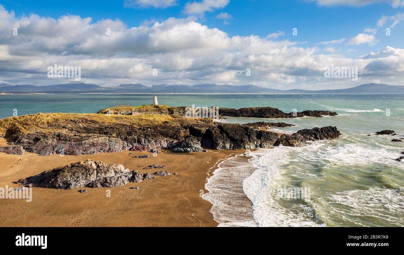 Ein Blick auf Twr Bach und die schneebedeckten Snowdonia Berge über Porth Twr Mawr auf Llanddwyn Island, Anglesey Stockfoto
