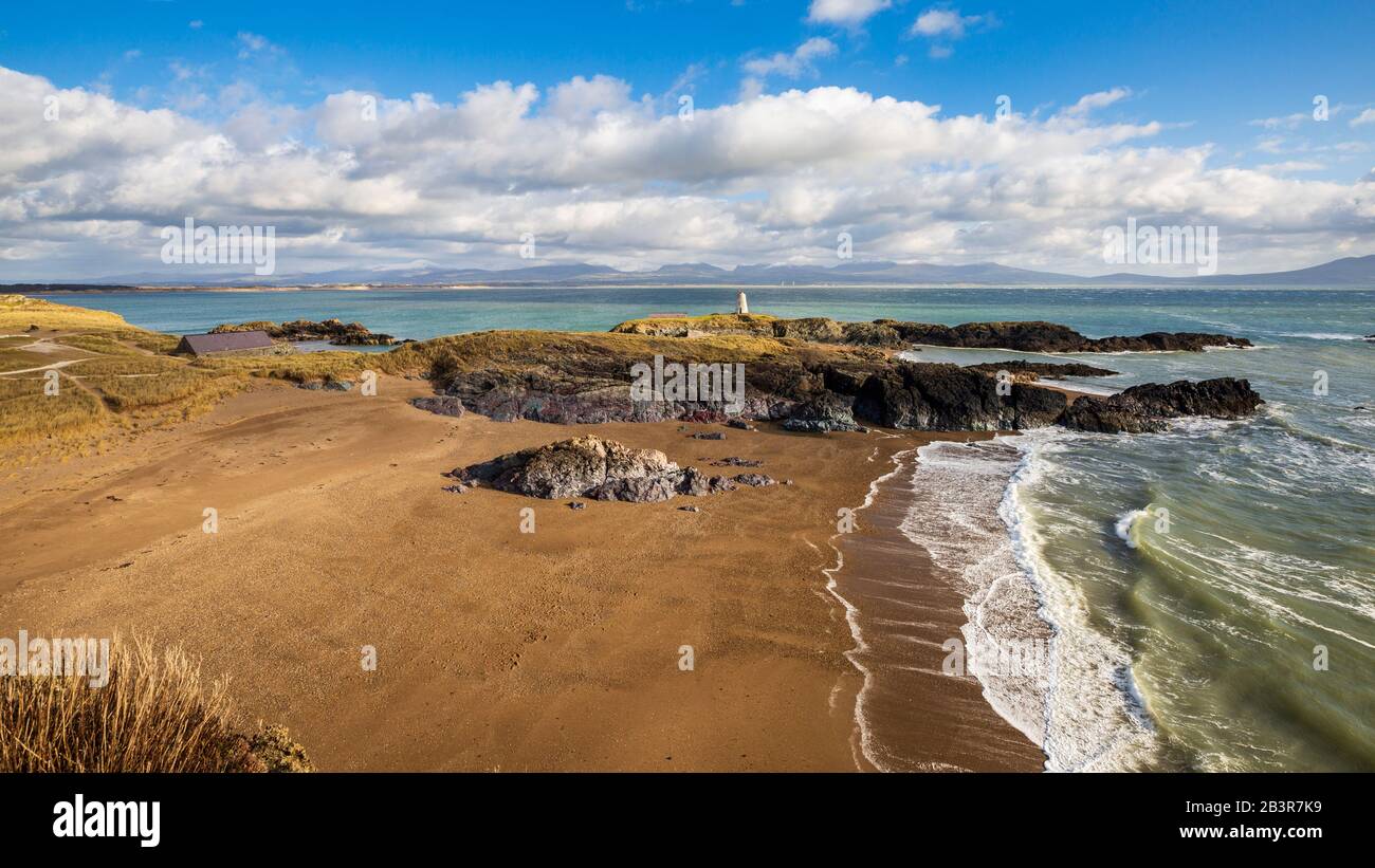 Ein Blick auf Twr Bach und die schneebedeckten Snowdonia Berge über Porth Twr Mawr auf Llanddwyn Island, Anglesey Stockfoto