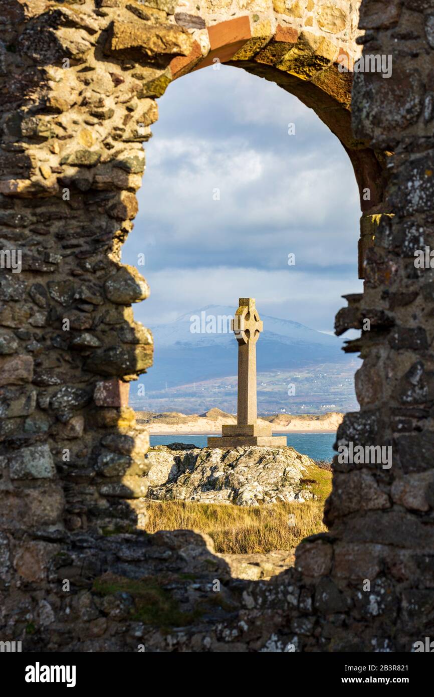 Das keltische Kreuz wurde durch die Ruinen der St. Dwynwen-Kirche auf der Insel Llanddwyn, Anglesey, Wales, gesichtet Stockfoto