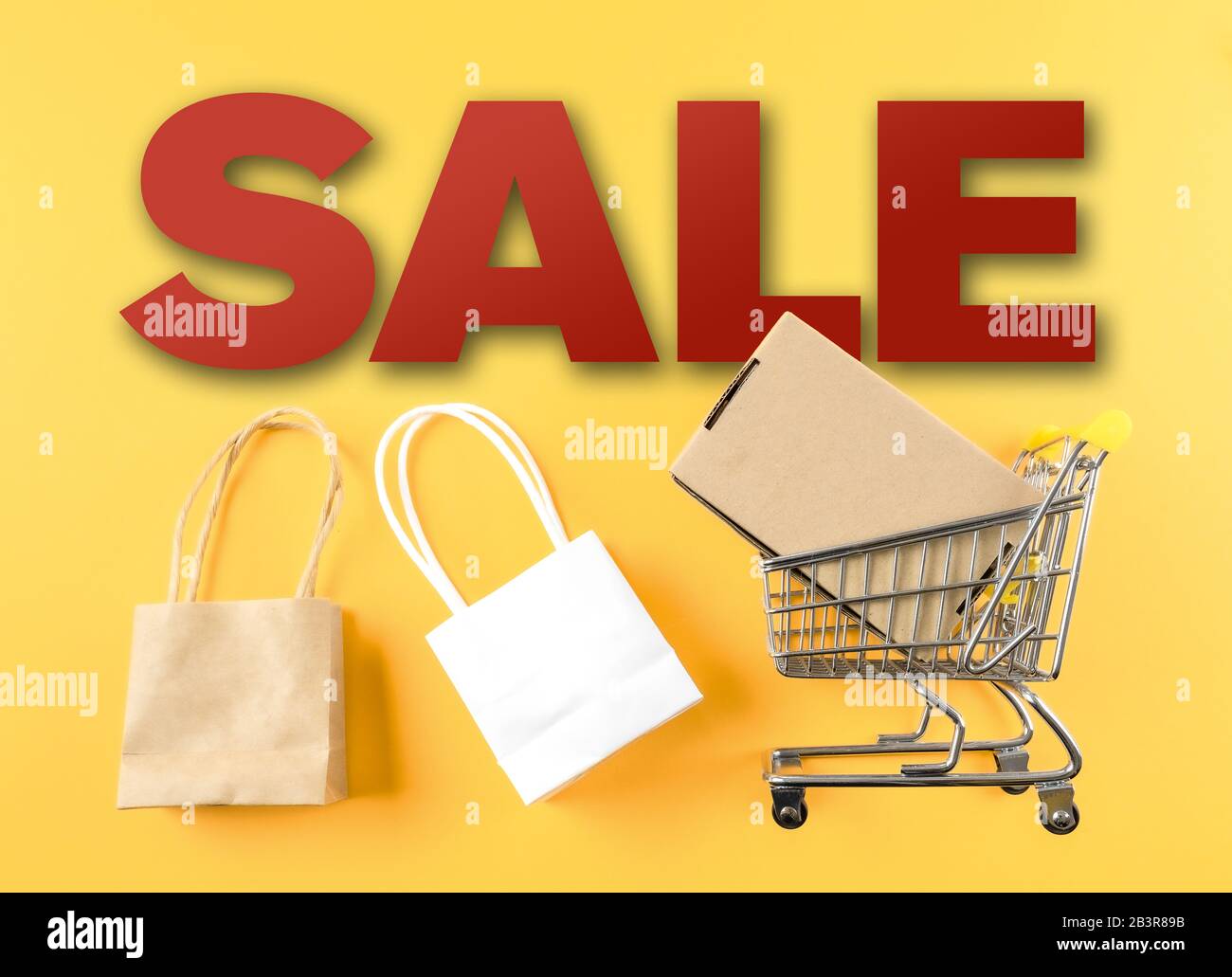 Marketingkonzept für den Einzelhandel mit WORTVERKAUF und Warenkorb und Taschen vor gelbem Hintergrund Stockfoto