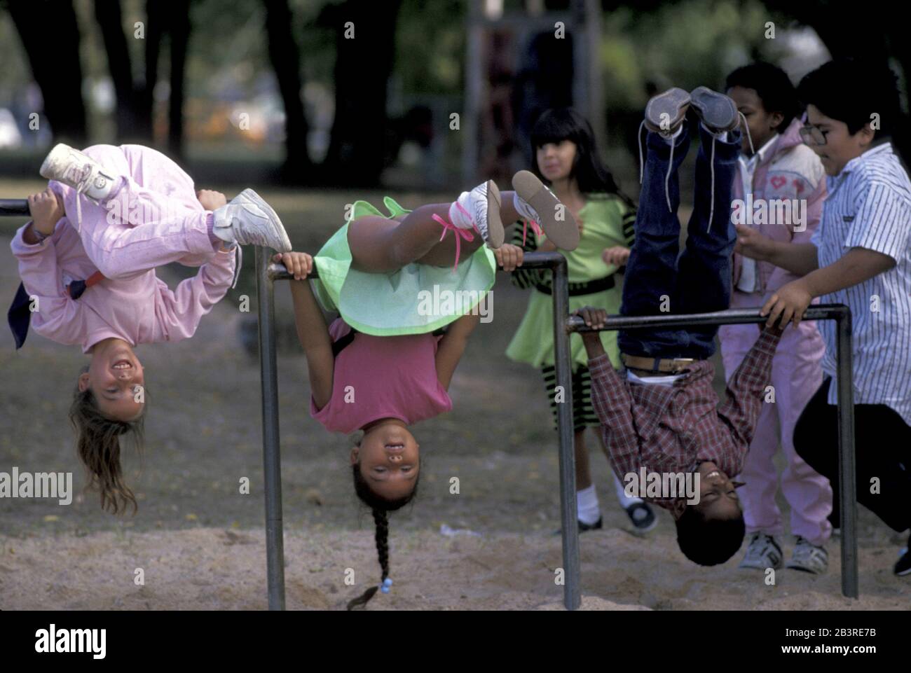 Austin Texas USA: Studenten hängen kopfüber an Metallstangen während der Aussparung auf dem Spielplatz der Grundschule. ©Bob Daemmrich Stockfoto