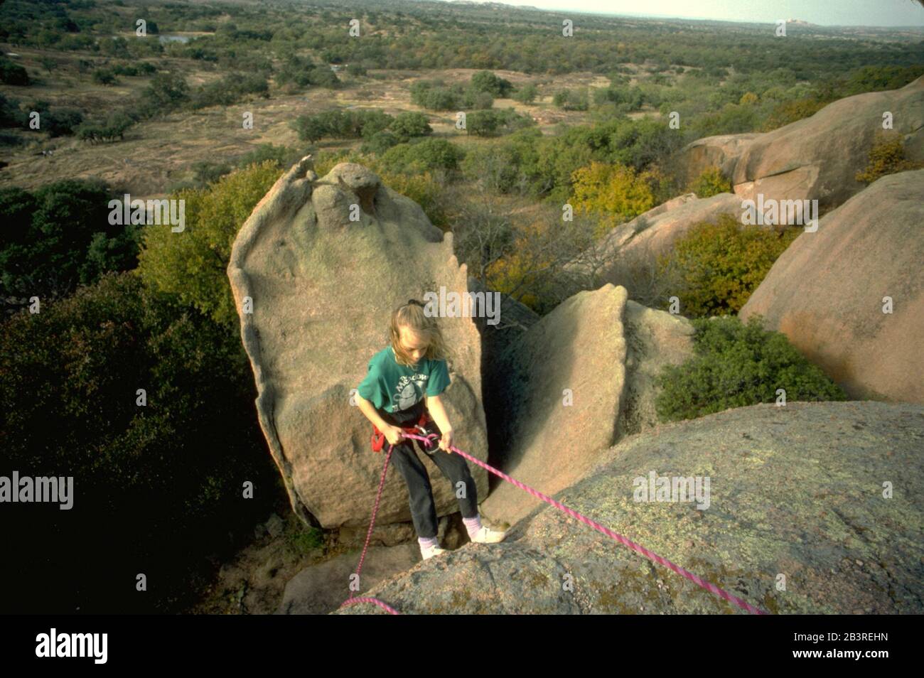 Enchanted Rock State Park, Texas, USA: Das neunjährige Mädchen fängt an, sich während einer Kletterstunde an der Klippe abzuseilen. ©Bob Daemmrich Stockfoto