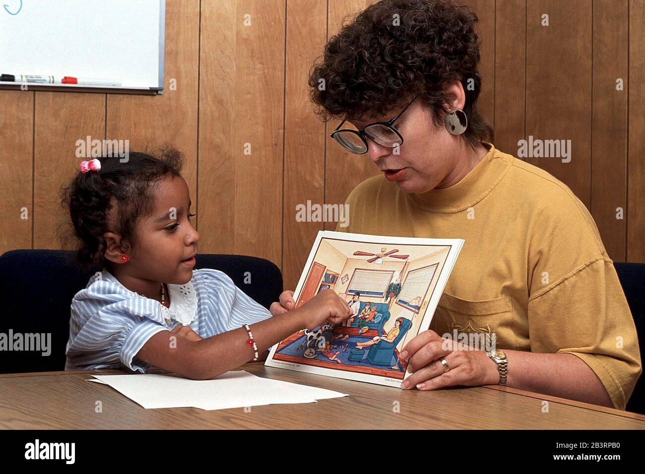 Austin Texas USA, um 1991: Der Sprachtherapeut einer öffentlichen Schule nutzt Bildband, um Antworten des 6-jährigen Hispanic während einer Einzeltherapie zu erhalten. ©Bob Daemmrich Stockfoto