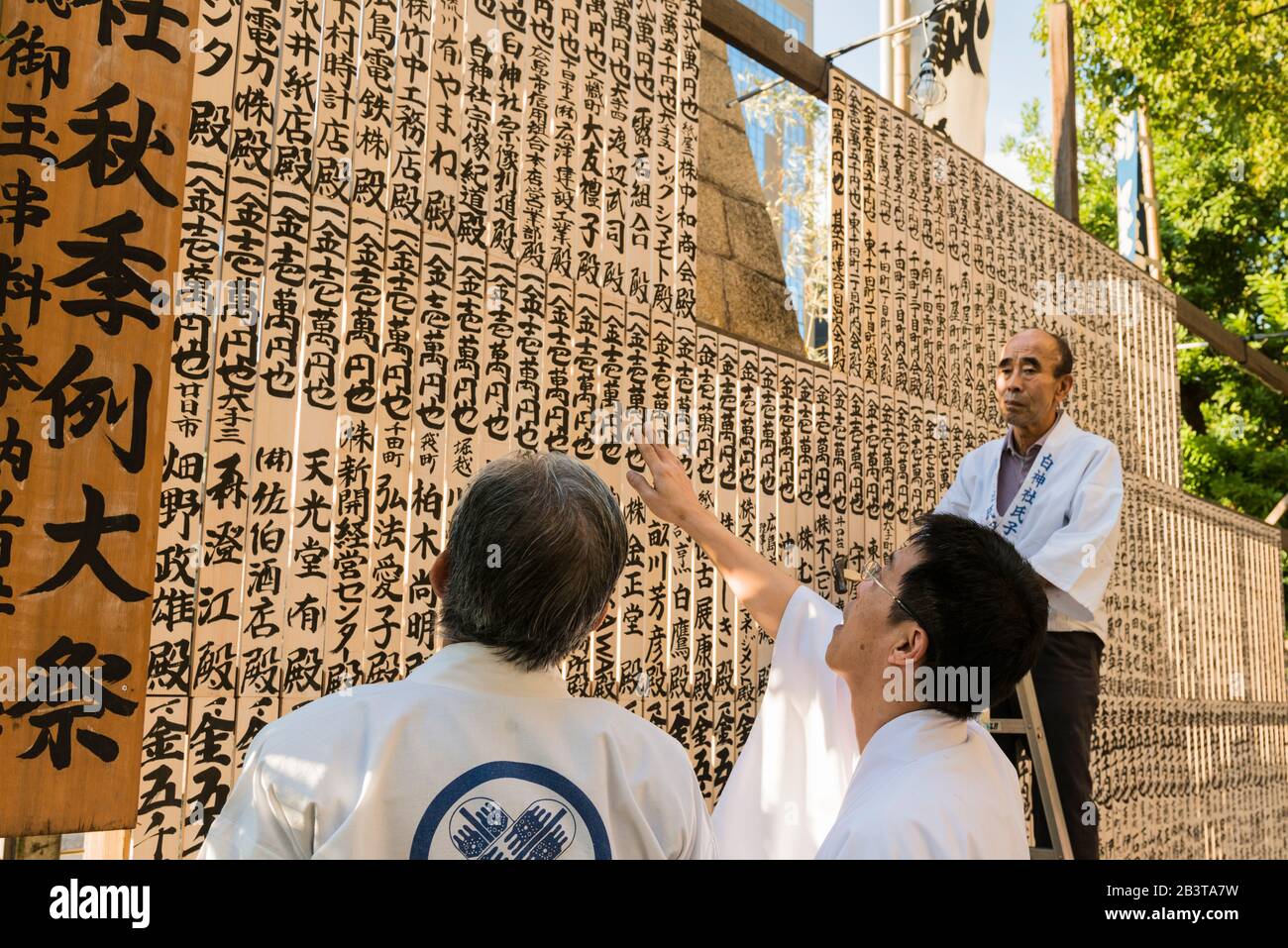 Sorasaya-jinja Schrein Herbstfest, Hiroshima, der Priester (Zentrum) fragt, ob der Mann auf der Leiter die Gebetstafeln in der richtigen Reihenfolge aufgenagelt hat. Stockfoto
