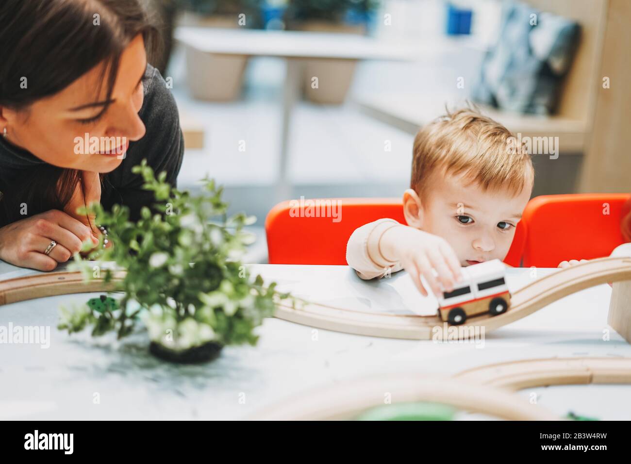 Süßes Kleinkind mit Mutter spielt mit Spielzeug im Spielzimmer im Einkaufszentrum Stockfoto