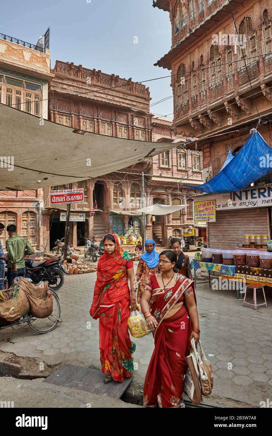 Frauen in bunten Saris schlendern durch die Straßen von Bikaner mit typischen Havelis, Rajasthan, Indien Stockfoto