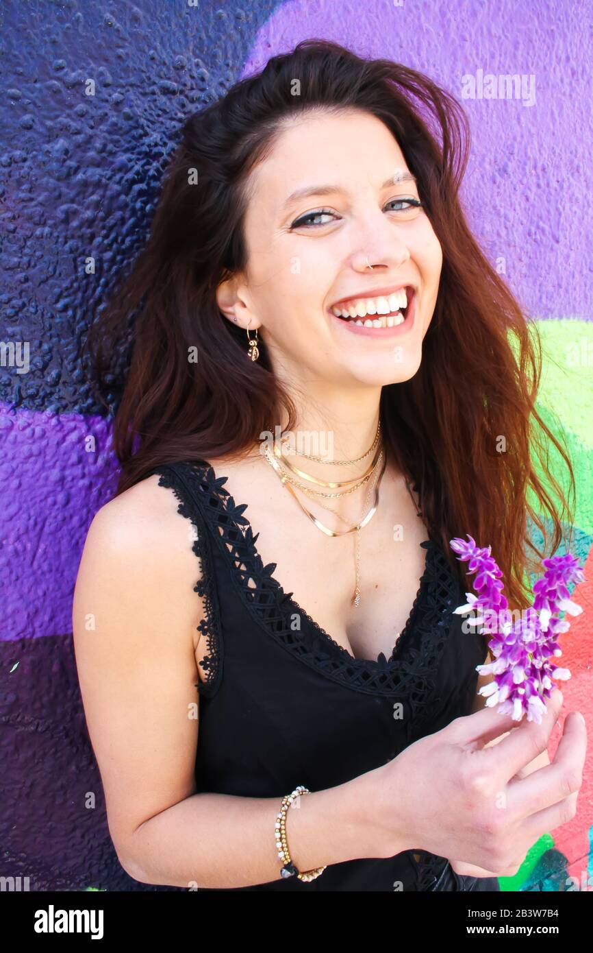 Junge Frau mit blauen Augen, die Blumen halten und vor der Kamera lachen. Stockfoto