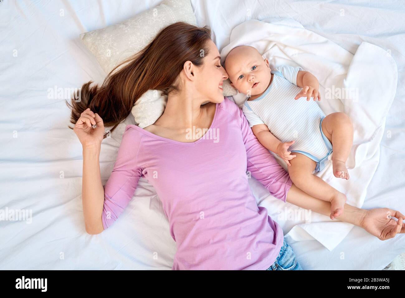 Junge Erwachsene Frau, die ihr kleines neugeborenes Baby betrachtet Stockfoto