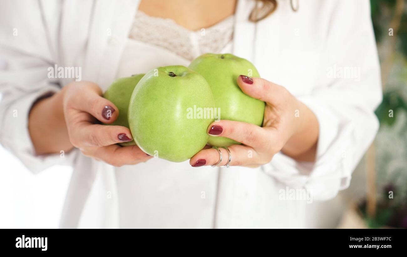 Nahaufnahme der weiblichen Hände mit drei grünen Äpfeln Stockfoto