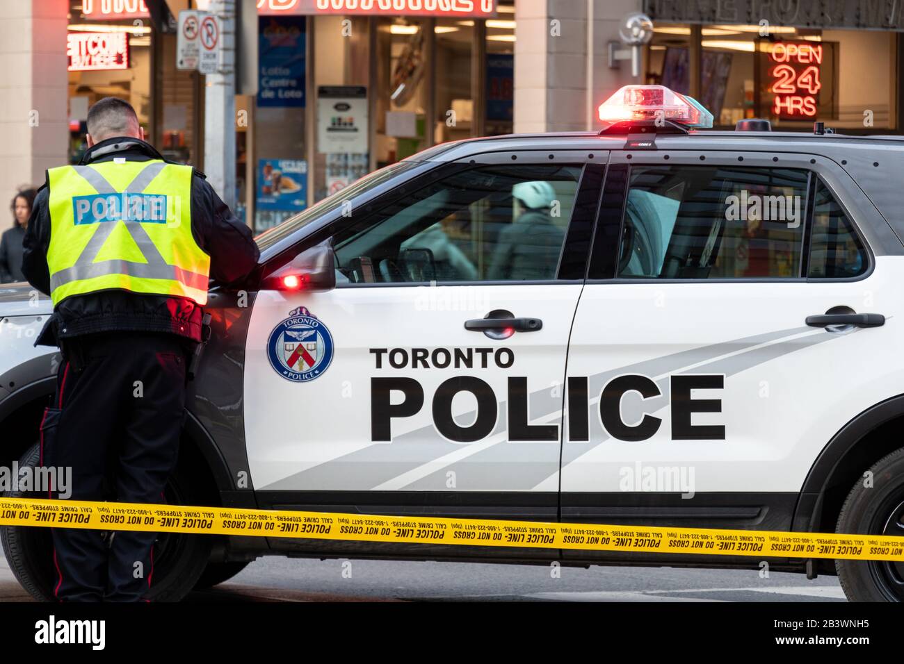 Toronto Polizeibeamter, der einen Bericht über seinen Kreuzer schreibt, während er auf einem Tatort, hinter einer Polizeilinie in der Innenstadt von Toronto, war. Stockfoto