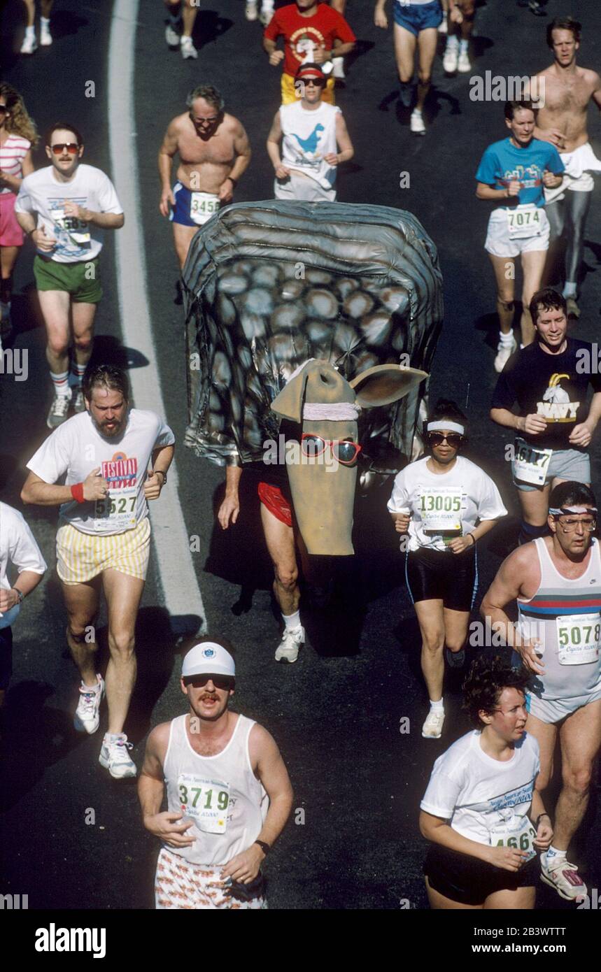 Austin Texas USA: Läufer in regulärer Laufausrüstung umgeben Läufer, die im jährlichen Capitol 10.000 Footrace in und um die Innenstadt als Gürteltier verkanzelt sind. ©Bob Daemmrich Stockfoto