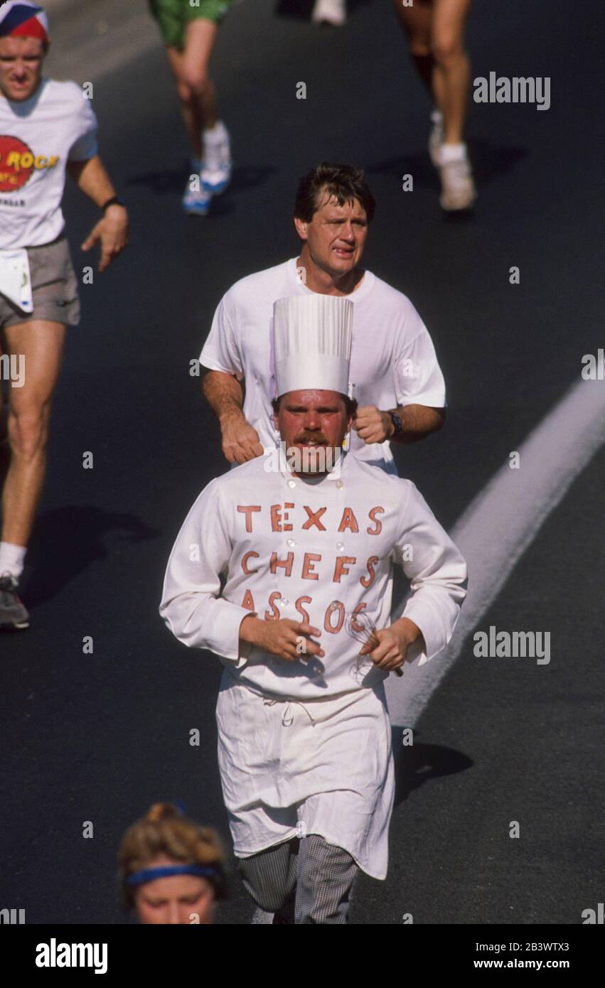 Austin Texas USA: Läufer in regulärer Laufausrüstung umgeben Läufer in Kostümierungen mit Kochmütze, Schürze und T-Shirt der Texas Chefs Association im jährlichen Capitol 10.000 Footrace in und um die Innenstadt. ©Bob Daemmrich Stockfoto