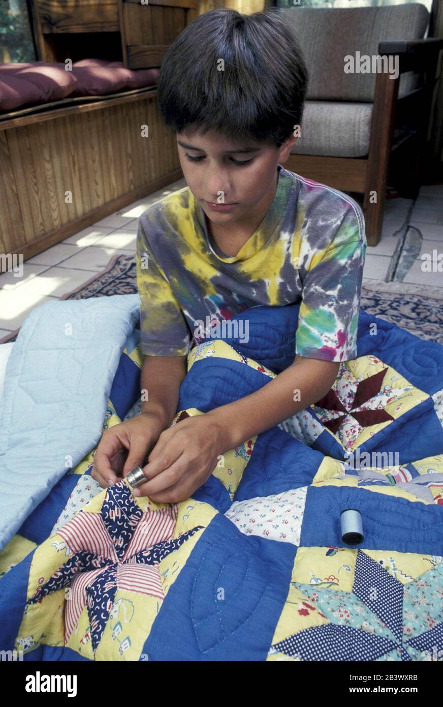 Austin Texas USA: Hispanischer Junge, der eine Nadel, einen Faden und ein Flint verwendet, während er einen Quilt zusammenstellt. ©Bob Daemmrich Stockfoto