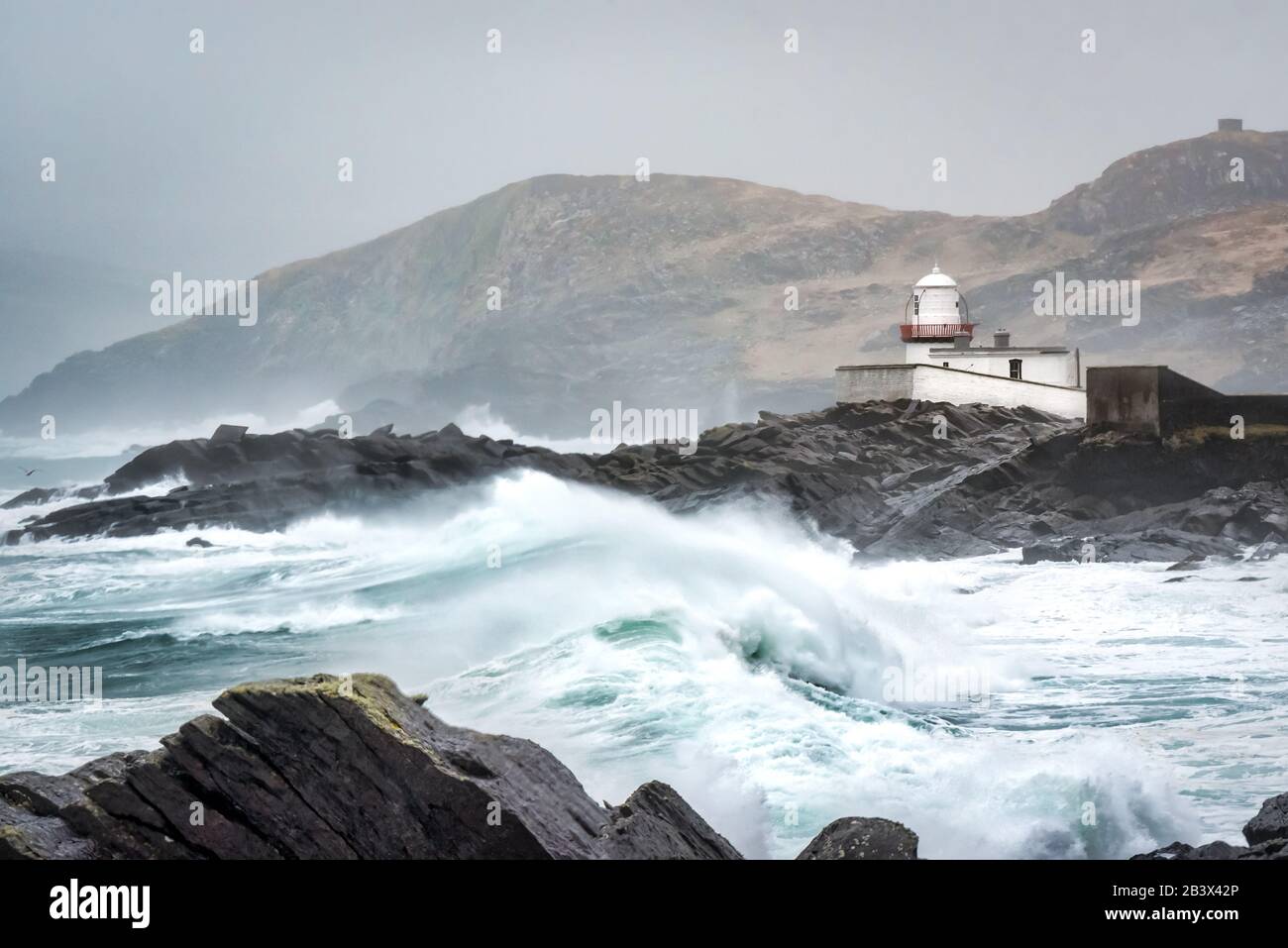 Stürmische Meere und hohe Wellen, die auf den Felsen vor dem Leuchtturm von Valentia im County Kerry Ireland abstürzen Stockfoto