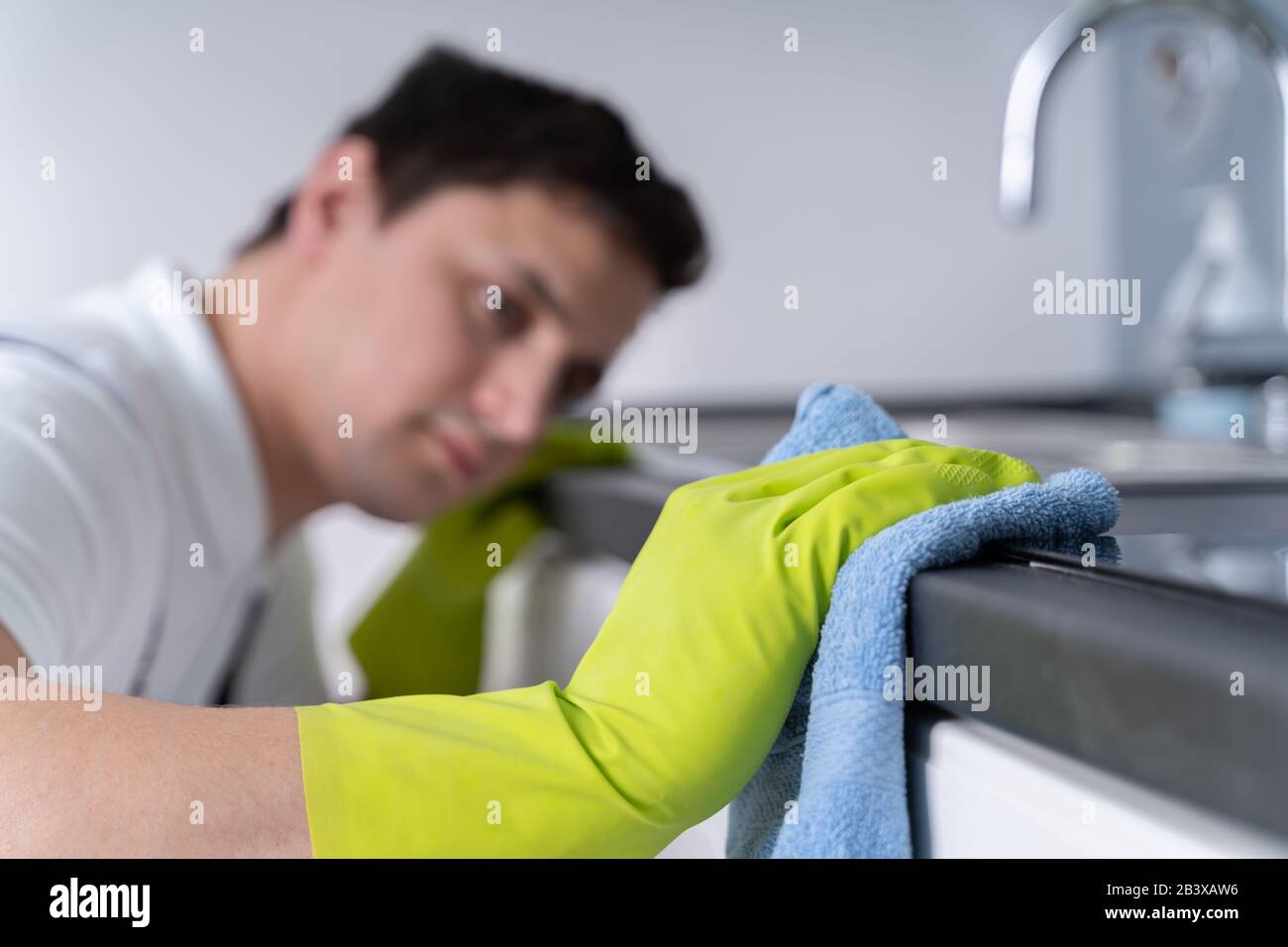 Junger Reiniger Mann Mit Schürze Reinigen Schmutzige Küche Arbeitsplatte Stockfoto