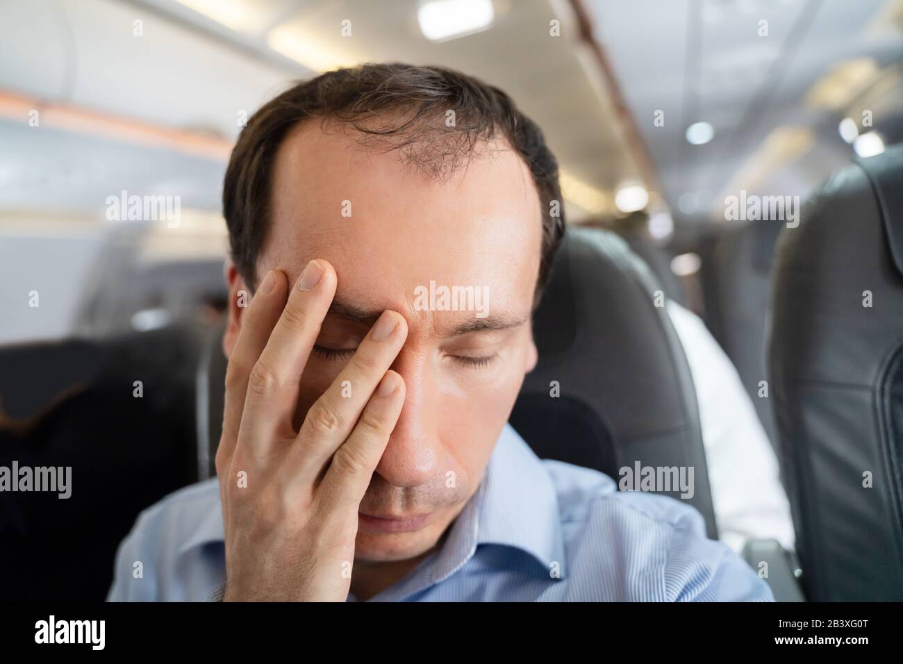 Junger Mann, Der An Einer Luftkrankheit Im Flugzeug Leidet Stockfoto