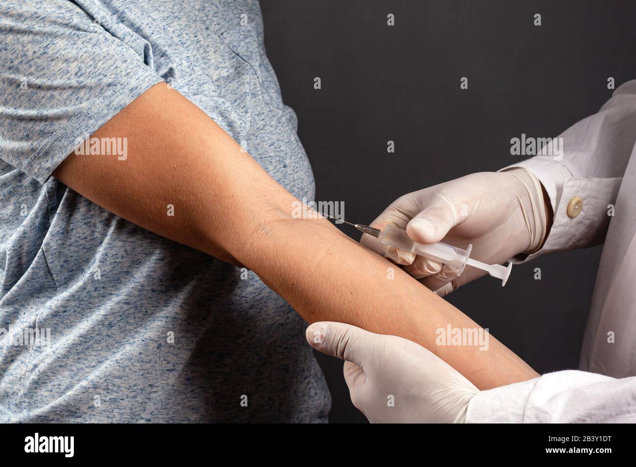 Der Arzt verabreicht einem kranken Patienten eine Injektion in eine Behandlung mit dunklem Hintergrund für virale und bakterielle Atemwegserkrankungen, Kovid-19-Impfung. Stockfoto