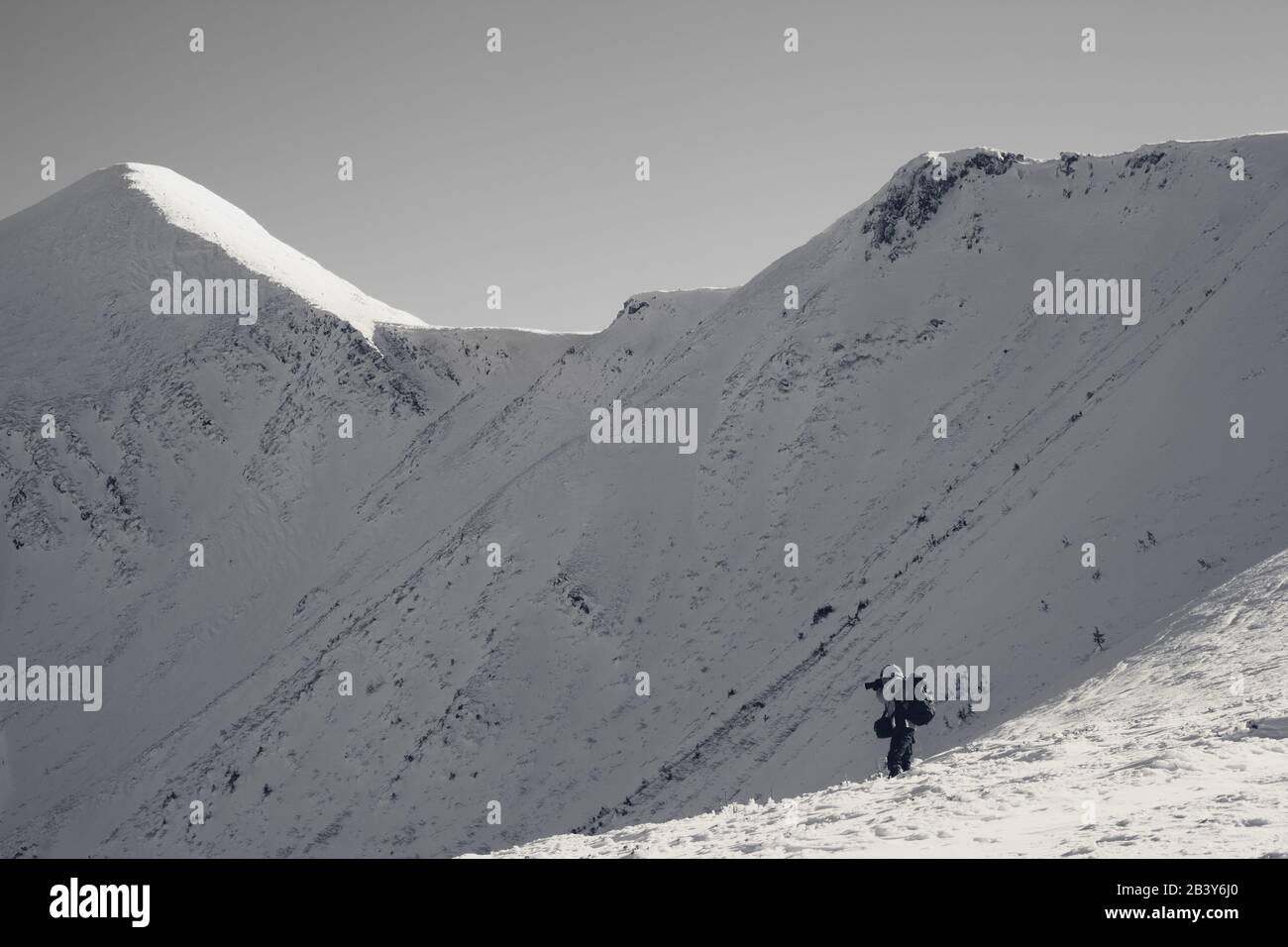 Fotograf fotografiert in schneebedeckten Bergen bei schönem Sonnenwintertag. Mount Hoverla im Hintergrund. Karpatengebirge, Ukraine. Schwarz-weiß Retro t Stockfoto