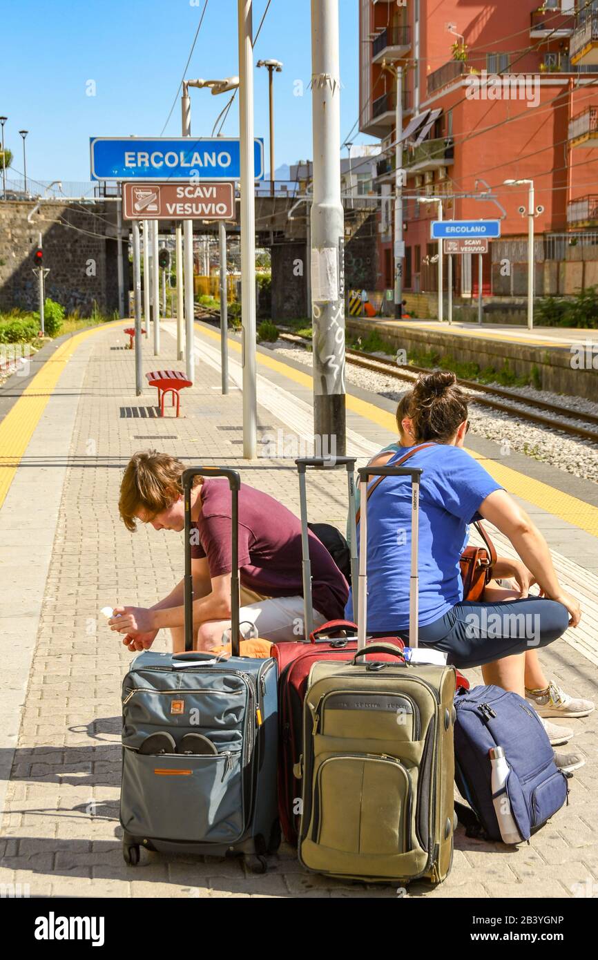 Ercolano, IN DER NÄHE VON NEAPEL, ITALIEN - AUGUST 2019: Gruppe junger Leute mit Gepäck, die auf einen Zug am Bahnhof Ercolano in der Nähe von Neapel warten Stockfoto