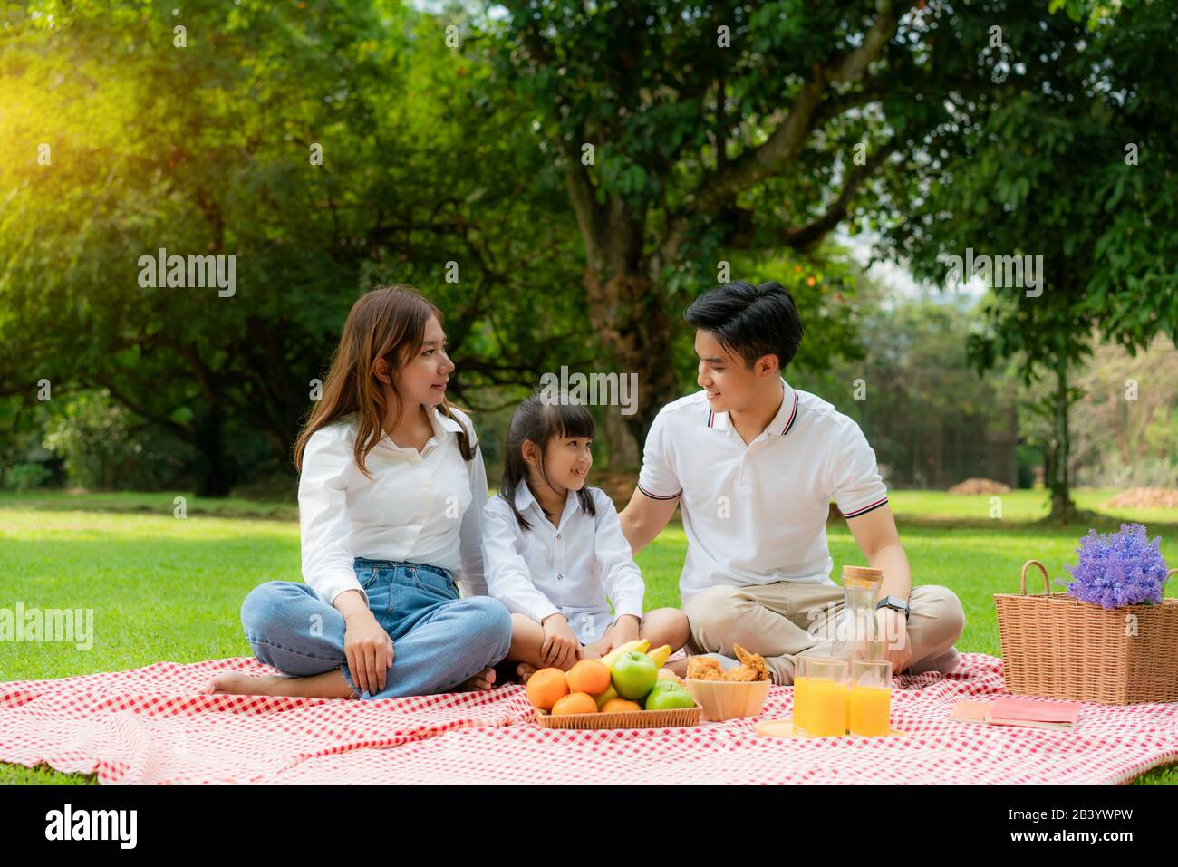 Asiatische Teenager Familie fröhlicher Urlaub Picknick-Moment im Park mit Mutter und Tochter, die Vater anschaut und lächelt, um glücklich zu verbringen Urlaub Zeit togerter ich Stockfoto