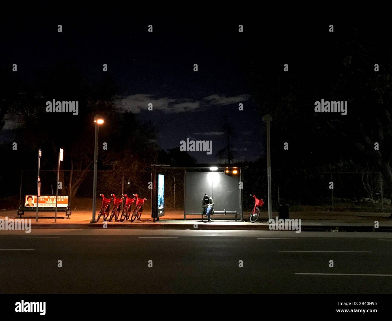 Eine Person wartet auf einen Bus neben einer Reihe von Sprungfahrrädern. Stockfoto