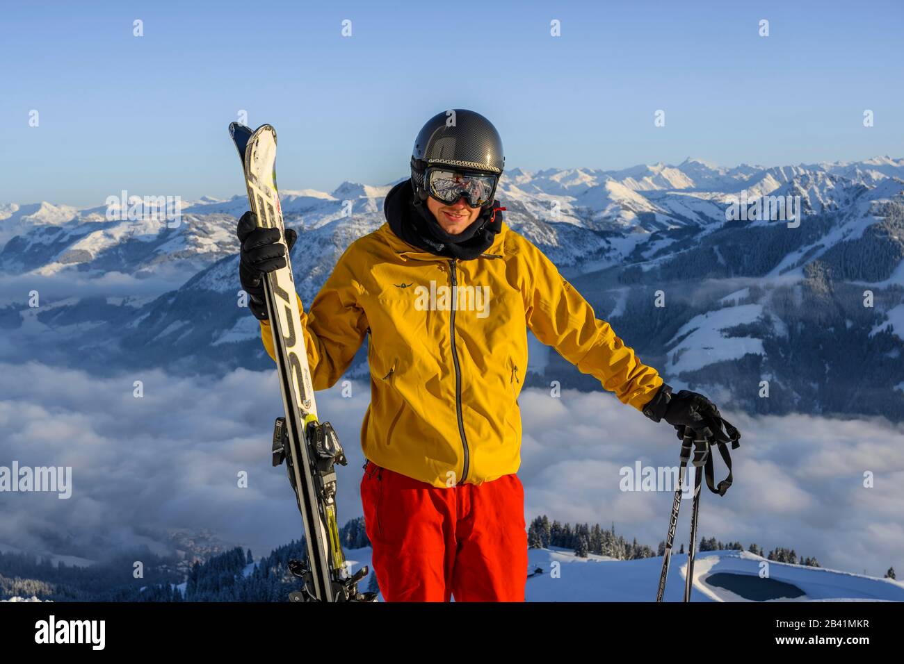 Skifahrer vor dem Bergpanorama, hält Ski, schaut in die Kamera, Gipfel hohe Salve, SkiWelt Wilder Kaiser Brixenthal, Hochbrixen, Tyrol, Österreich Stockfoto