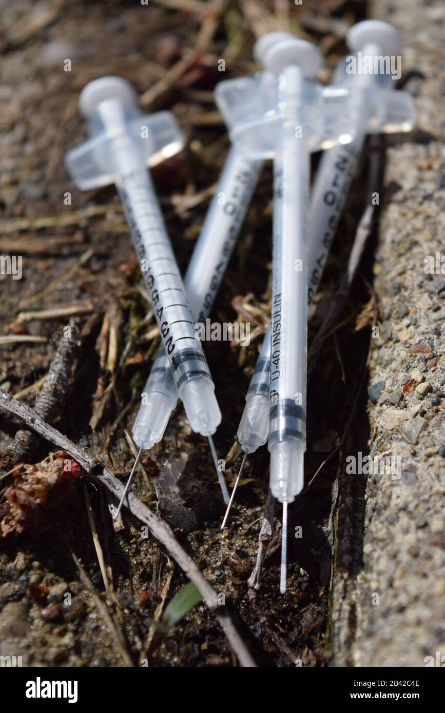 Gebrauchte Nadeln, die in einem öffentlichen Park entsorgt wurden. Opioidkrisenverschmutzung. Gefahr ansteckender Krankheiten Stockfoto