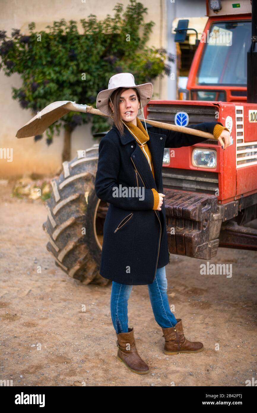 Schönes Mädchen mit einer Schaufel vor einem Traktor Stockfoto