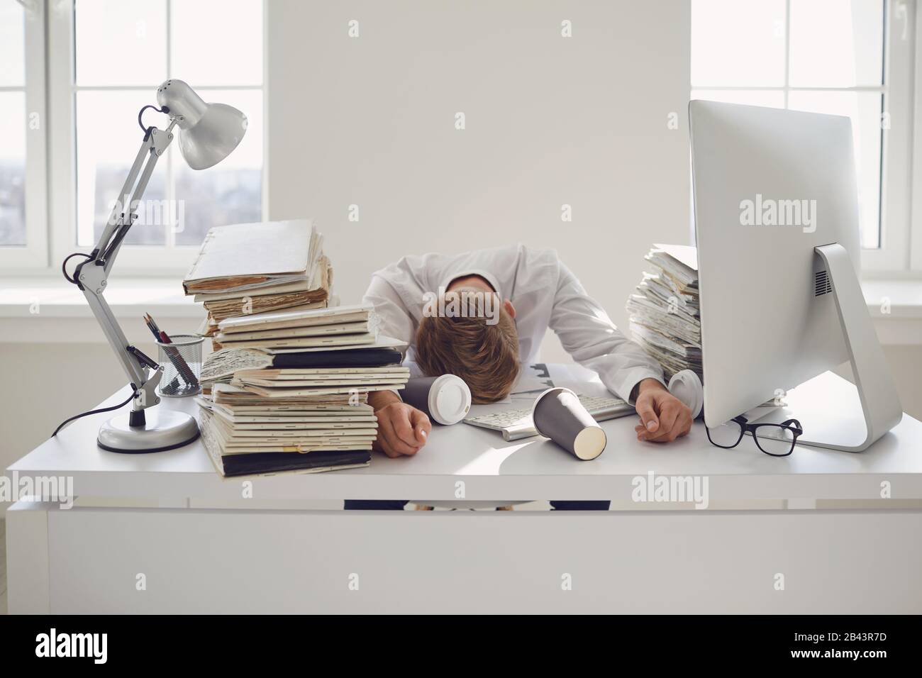 Müde beschäftigte Geschäftsleute, die mit einem Computer an einem Tisch schlafen. Stockfoto