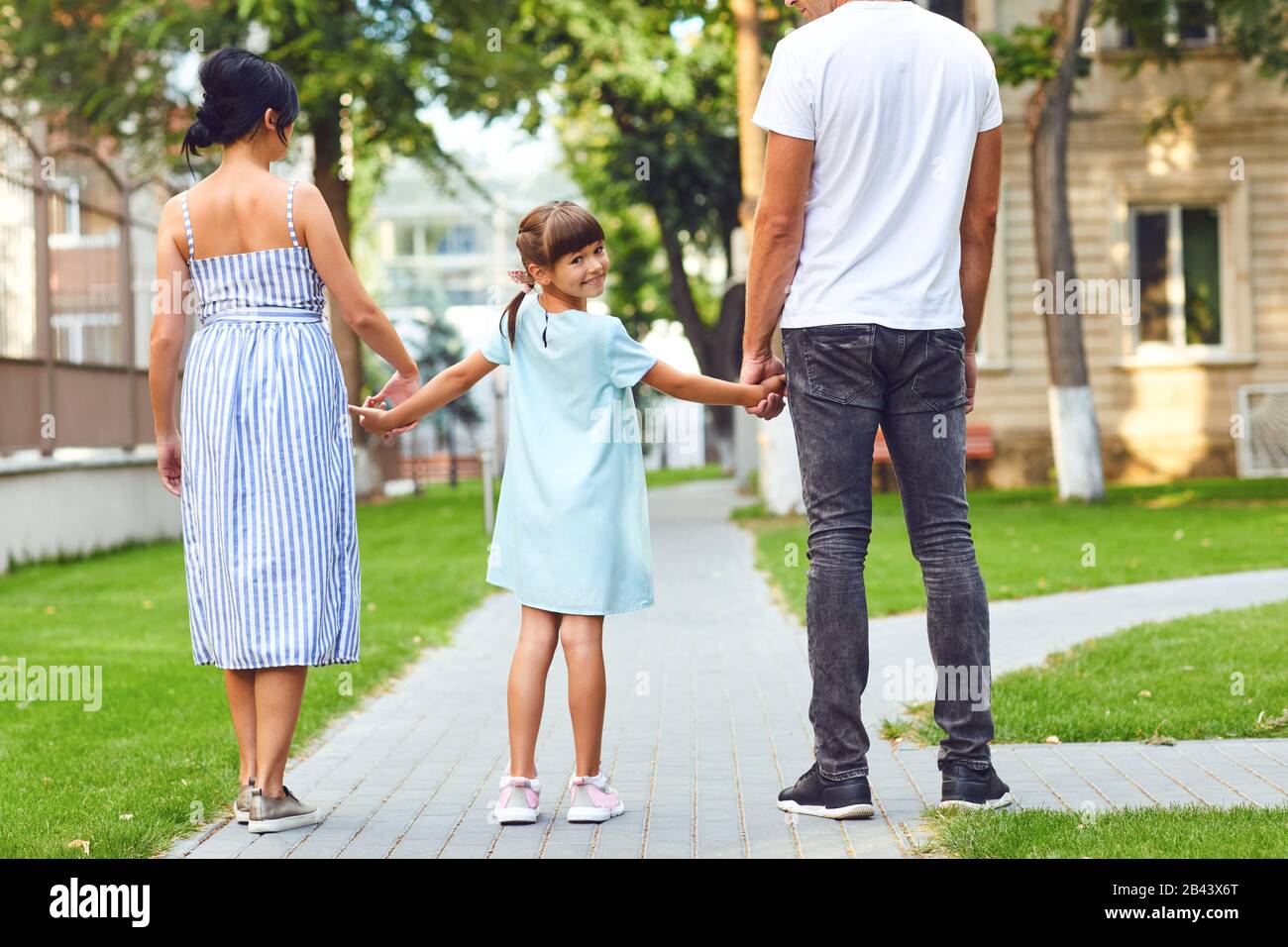 Fröhliche Familie, die in der Straße der Stadt zusammen spazieren geht Stockfoto