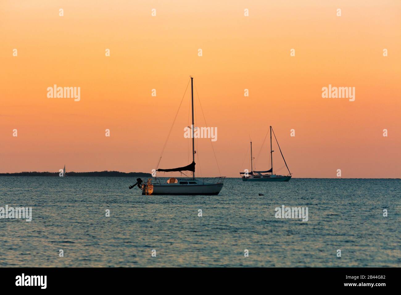 Zwei Segelboote dockten bei Sonnenuntergang im Meer über den Strand. Stockfoto