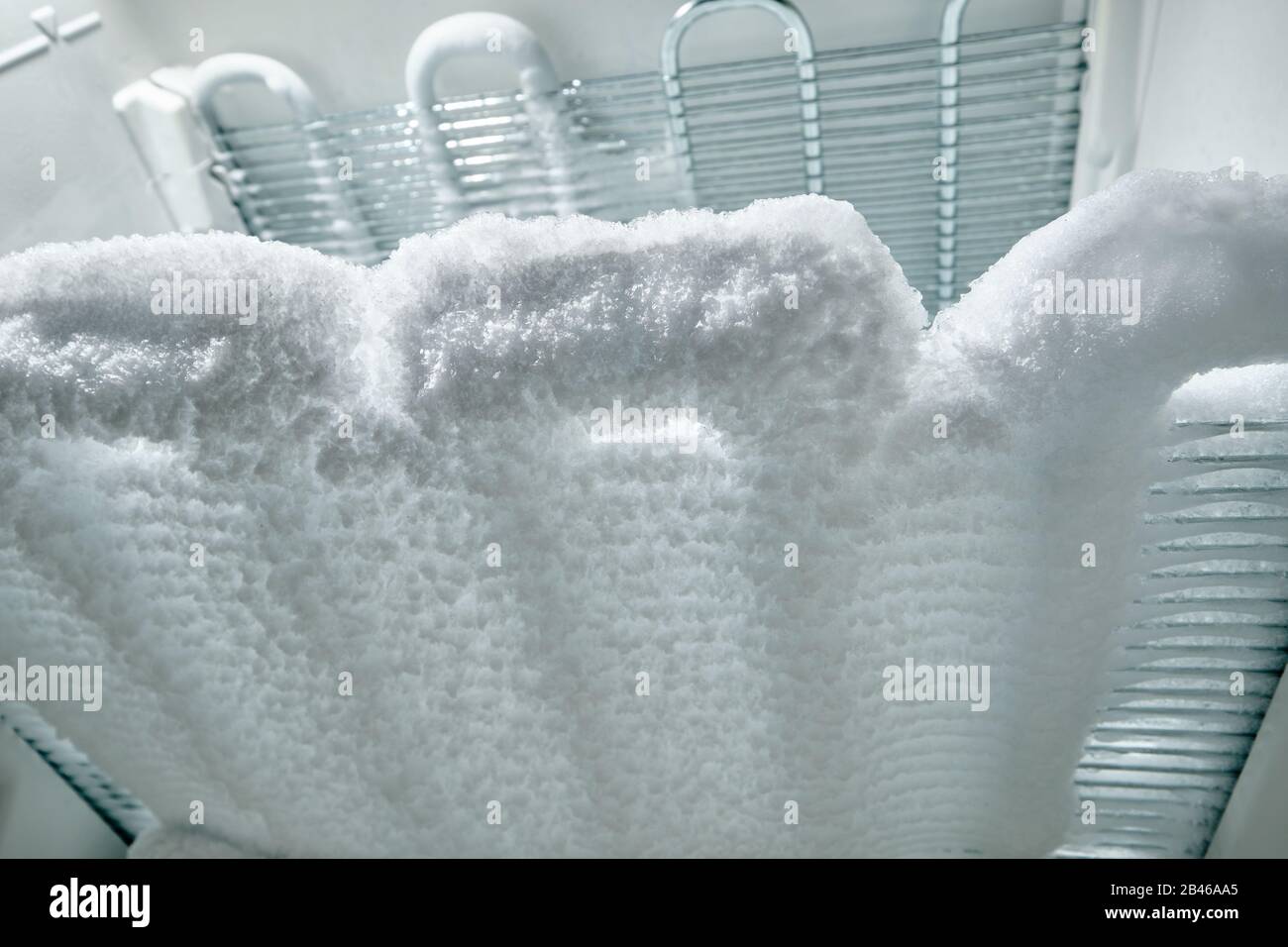 Zeit bis zum Abtauen: Blick in den Gefrierschrank auf Kühlschlangen, die vollständig mit Eis bedeckt sind. Stockfoto