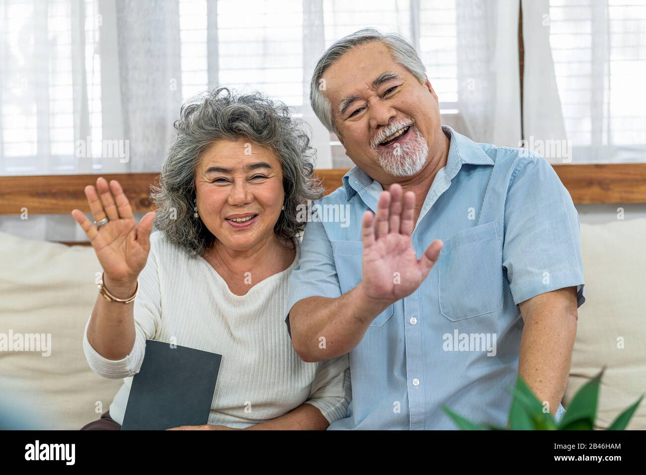Asiatisches Paar Großelterngruß und sprach mit Enkelin mit fröhlichen Gefühlen per Videotelefon per Handy im Haus, In Long Live und Ältester Stockfoto