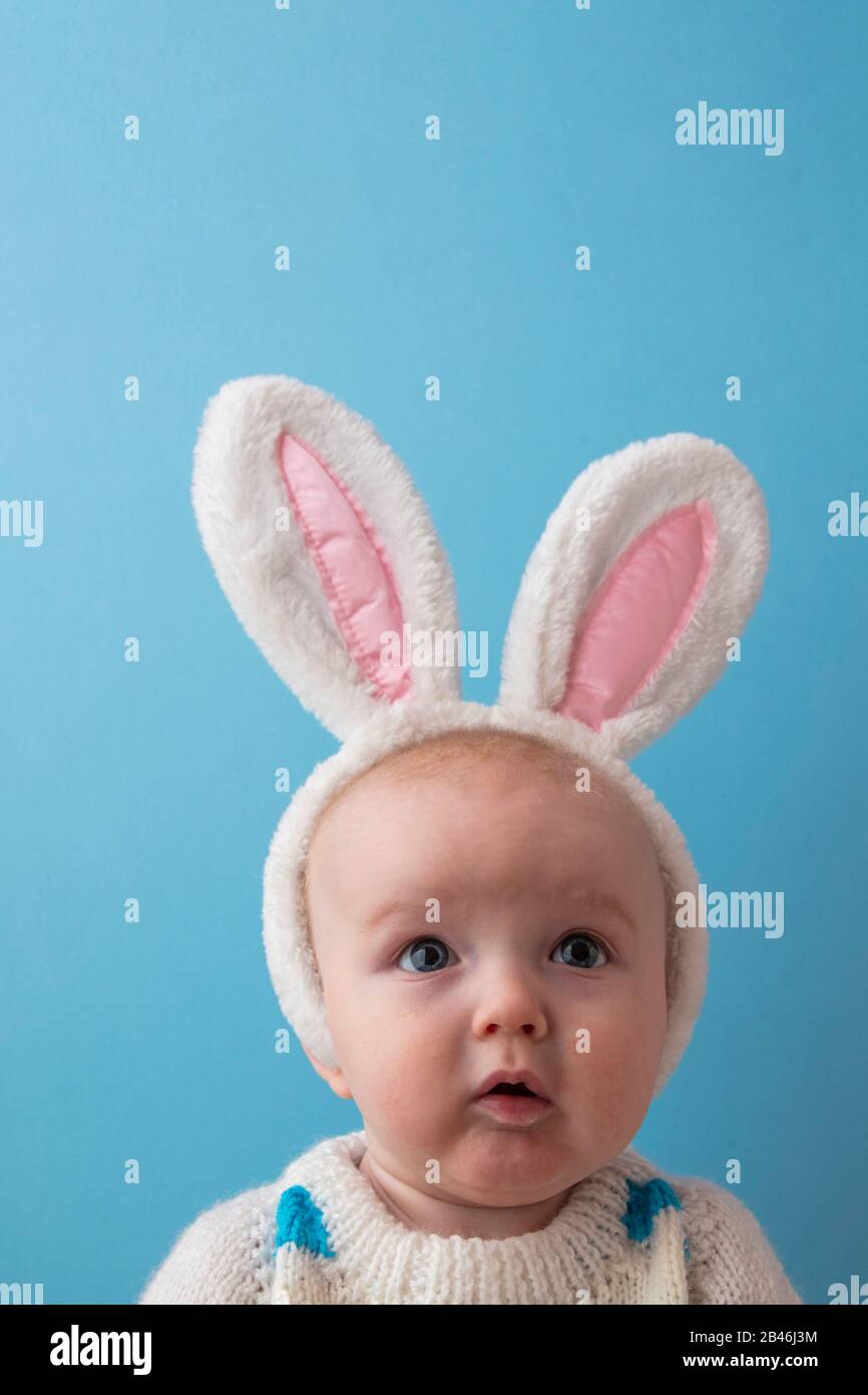 Süßes kleines Baby mit weißen easter Hunny Ohren vor blauem Hintergrund Stockfoto