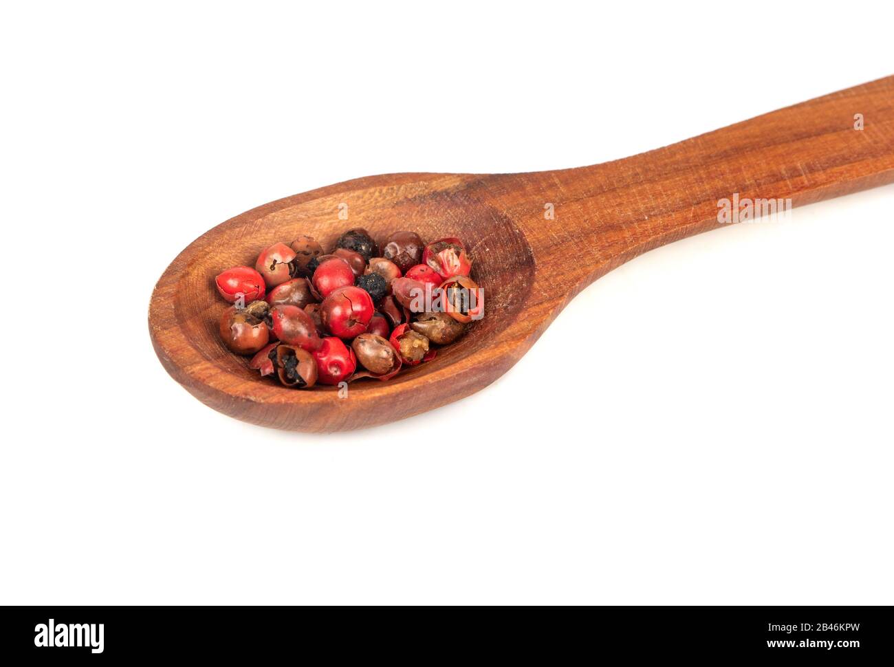 Rote Paprika Erbsen in hölzernen Löffel schließen bis auf weißem Hintergrund Stockfoto