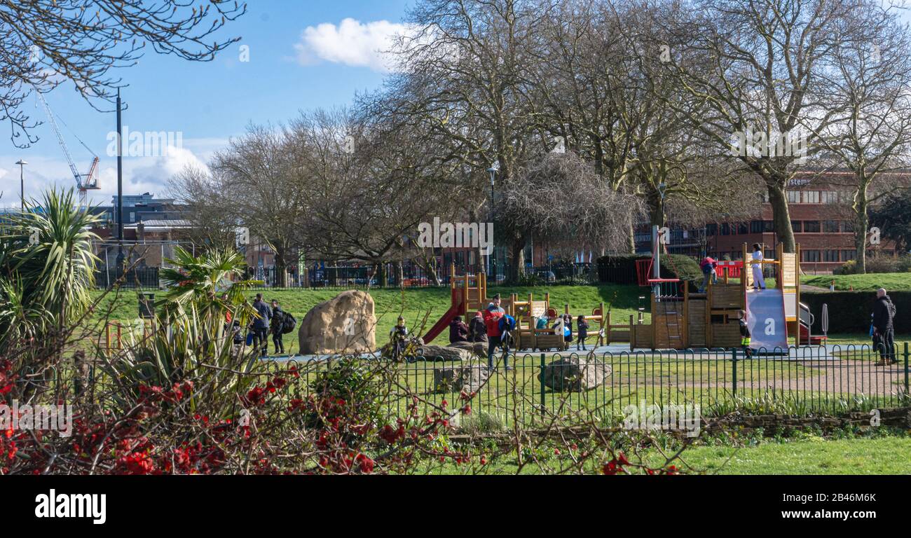 Kinder, die die Spielbereiche im Salt Hill Park, Slough, genießen, während ihre Eltern darauf schauen. Sonniger Tag, Spätwinter. Stockfoto