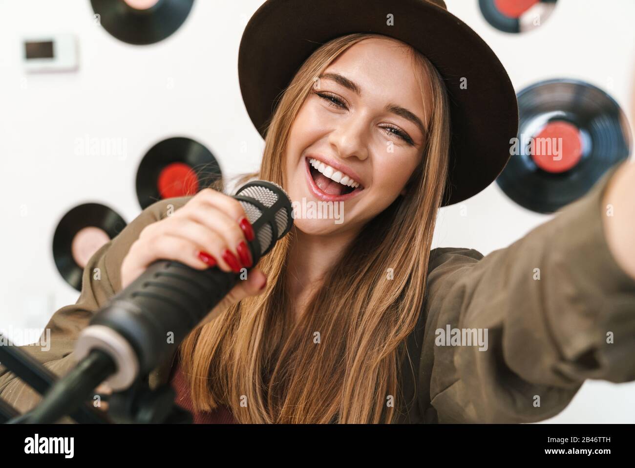 Bild einer jungen glücklichen kaukasischen Frau, die bei Radiosendungen auftritt und gleichzeitig Podcast-Aufnahmen für die Online-Show macht Stockfoto