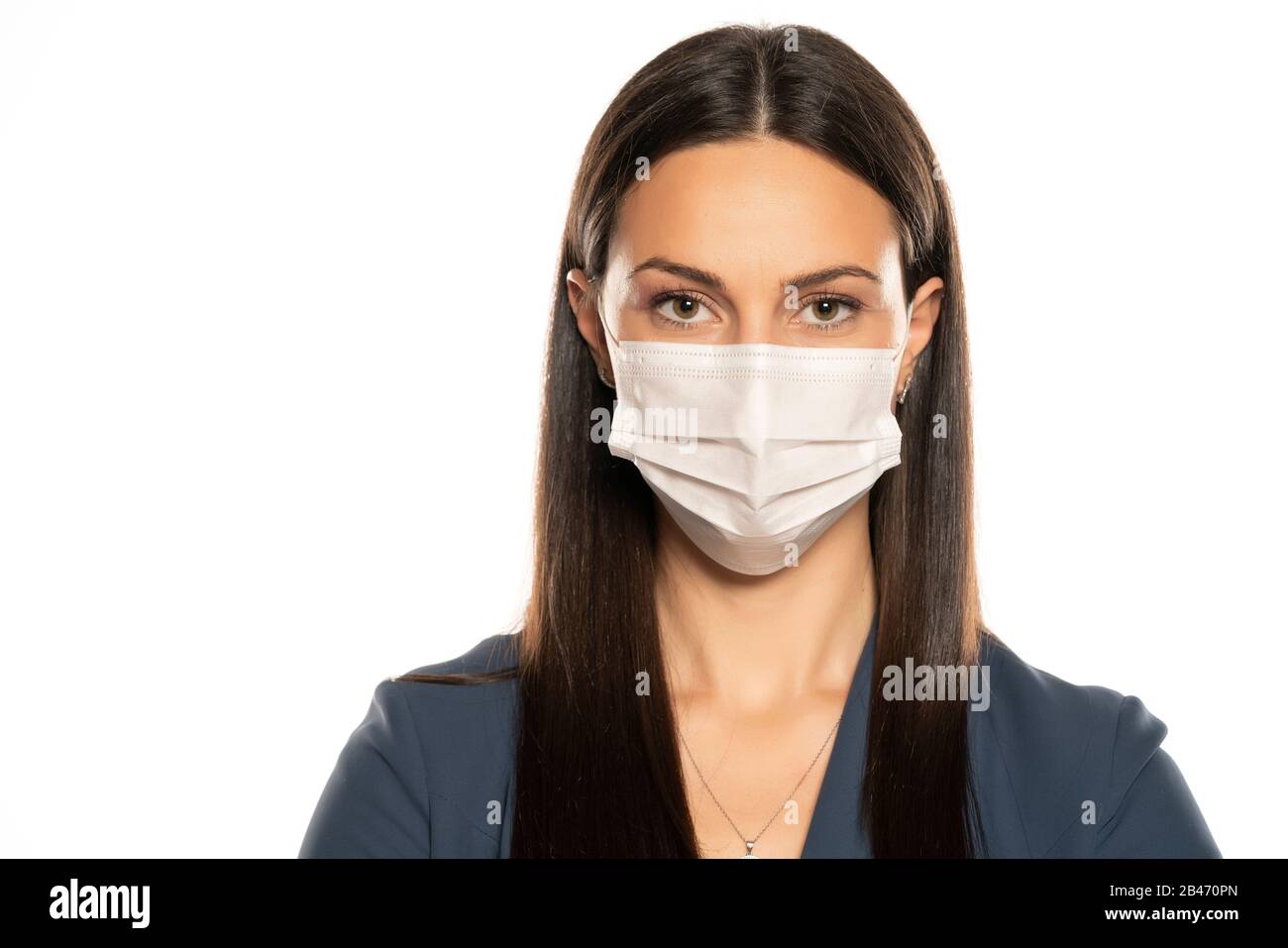Schöne junge Frau mit Schutzmaske auf dem Gesicht auf weißem Hintergrund Stockfoto